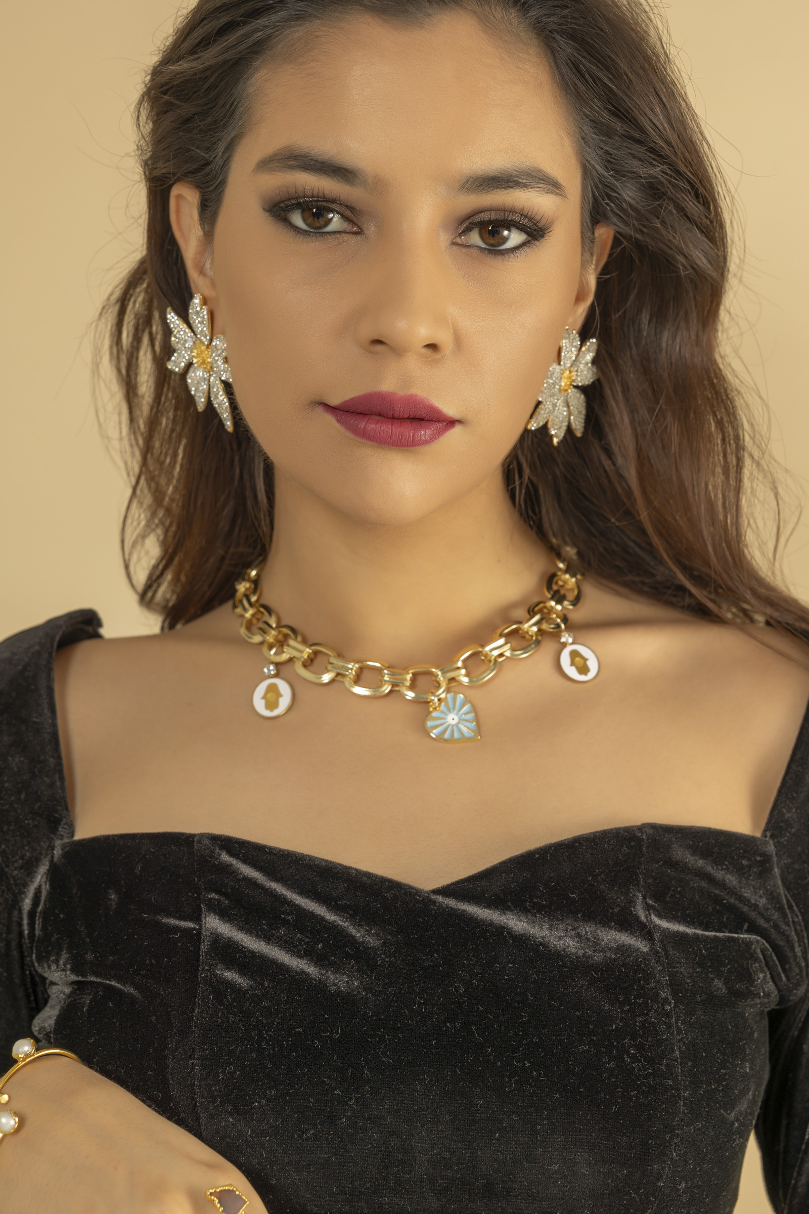 Camila wearing crystal flower earrings and a charm necklace
